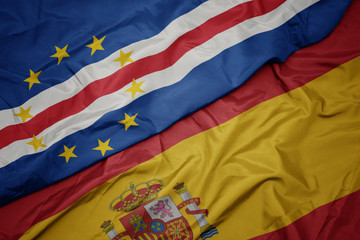 waving colorful flag of spain and national flag of cape verde.