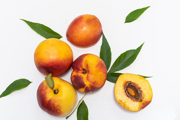 Fresh ripe organic nectarines with leaves on white background. Harvest concept. Healthy and tasty summer dessert.