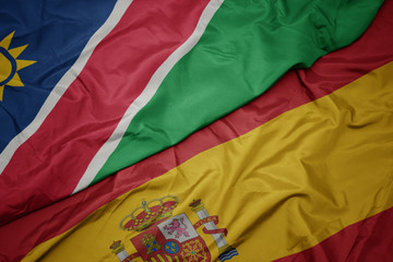 waving colorful flag of spain and national flag of namibia.