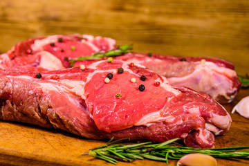 Raw ribeye steak, spices, rosemary and garlic on cutting board