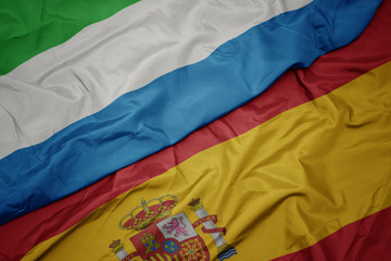 waving colorful flag of spain and national flag of sierra leone.