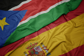 waving colorful flag of spain and national flag of south sudan.