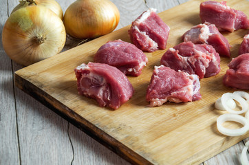Cubes of raw beef and onion on cutting board