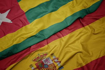 waving colorful flag of spain and national flag of togo.
