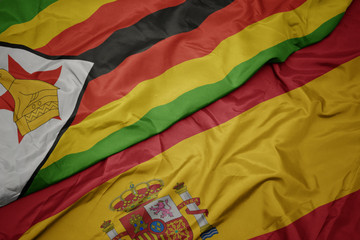 waving colorful flag of spain and national flag of zimbabwe.