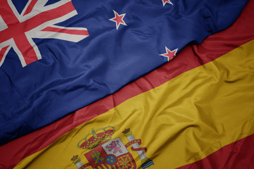 waving colorful flag of spain and national flag of new zealand.