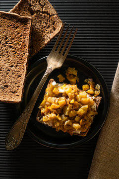 Dry bread fork and sofa with vegetable salad on chono background on a black plate