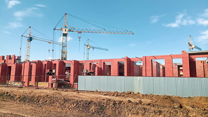 Large number of tower cranes are installed on the construction site, on a bright Sunny day.