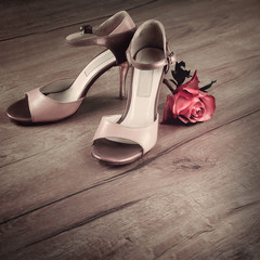 Argentine tango shoes and a rose on a wooden floor, space