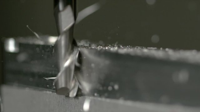 SLOW MOTION, MACRO, DOF: Sharp end mill drill shaves the side of an aluminium workpiece. Fine end mill drill of a CNC lathing tool cutting and shaving a piece of metal into an unfinished product.