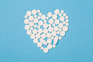 Assorted pharmaceutical medicine pills, tablets and capsules for the treatment of heart disease. Heart shape of pills.