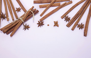 Cinnamon sticks and anise stars on a white pink background. Spices for drinks and food. Christmas still life. Flat light. Top view. With copy space for text.
