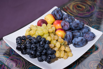 Grapes, plums and peaches on white the plate