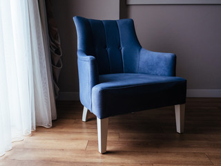 Blue armchair in the interior. Comfortable velor chair.