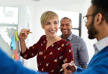 Portrait of a blonde short hair woman leading a diverse team of creative millennial coworkers in a...