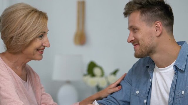 Loving mother caring for her grown-up son who come to visit her, missed him