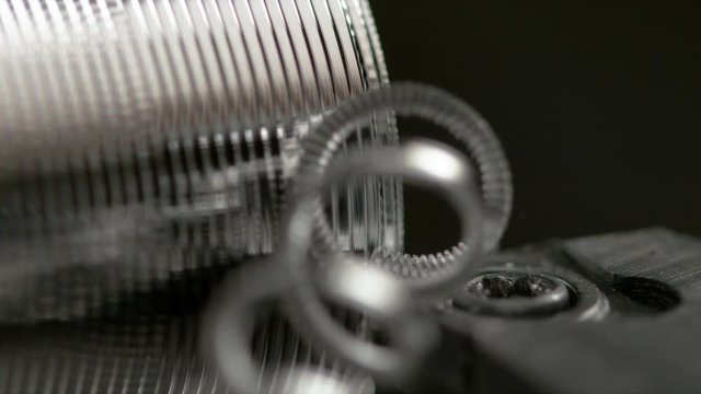 SLOW MOTION, MACRO, DOF: CNC machine slowly threading a small metal workpiece into a shiny bolt Sharp cutter carving deep grooves into a silver colored workpiece during thread cutting procedure.
