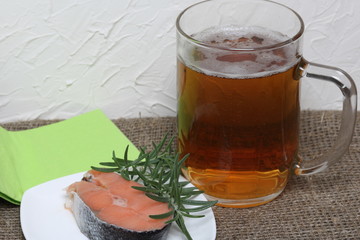 A glass of frothy beer and salmon steak with rosemary. View from above. Beer Festival.