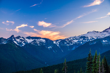 Alpenglow on clouds over a rugged mountain range in Mt. Rainier National Park.