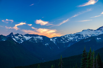 Alpenglow on clouds over a rugged mountain range in Mt. Rainier National Park.