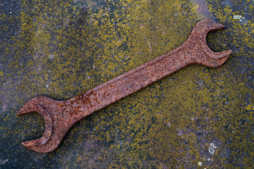 Rusty old wrench on a rusty surface