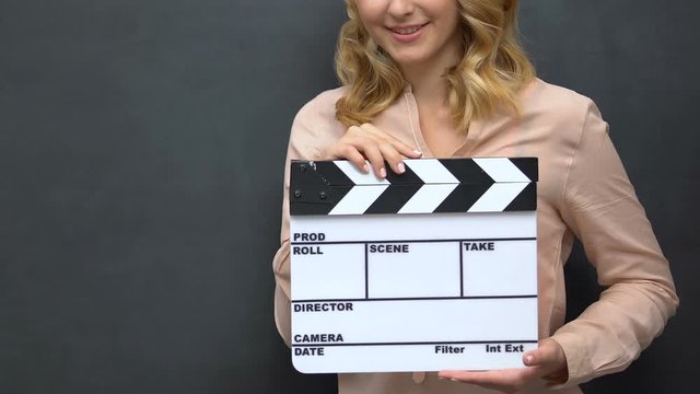 Young lady clapping with flapper isolated on blackboard background film shooting
