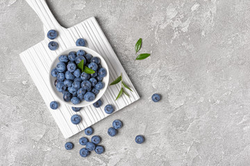 Fresh blueberry berries in white bowl on wooden board