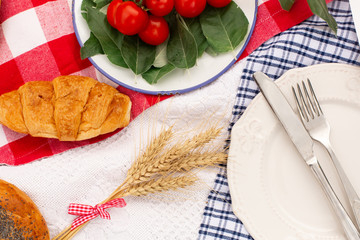 Stylish picnic on the green lawn. Fresh croissants and a teapot with tea on a bedspread near a wicker female hat. Instagram content