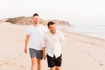 Young same sex couple walking on the beach