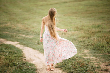 Fototapeta na wymiar Beautiful young girl with long hair in dress outdoors, cute woman walking in the park