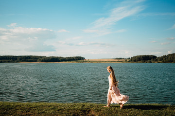 Beautiful young girl with long hair in dress outdoors, cute woman walking in the park