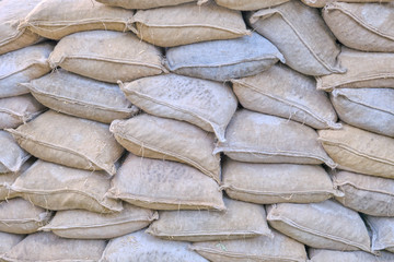 Background of full burlap dirty bags. Protective wall of sandbags. Piled sandbags for protection against natural disasters, texture.
