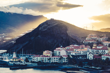Obraz premium Image of wind mills and solar panels on a hill with sunset sunlight breaking through clouds creating epic atmosphere
