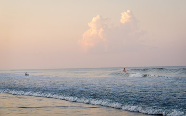 thunderheads loom on the distant horizon while kids engage in some surfing on the outer banks of north carolina