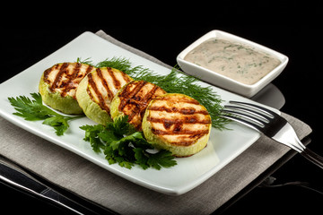 Concept for a healthy summer diet: baked zucchini with dill sauce