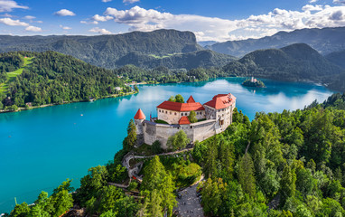 Bled, Slovenia - Aerial panoramic view of beautiful Bled Castle (Blejski Grad) with Lake Bled (Blejsko Jezero), the Church of the Assumption of Maria and Julian Alps at background on a summer day - obrazy, fototapety, plakaty