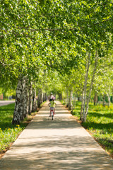 Fototapeta na wymiar Children on bicycles ride a bike path in the park. Selective focus, blur.