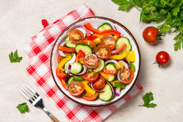Summer fresh vegetable salad on light table top view.