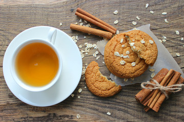 Homemade oatmeal cookies and a Cup of tea on an old wooden table, rustic style. Oatmeal and cinnamon sticks. Copy space.The view from the top.