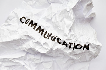 Crumpled white paper with the word communication printed in black. Concept of bad disrupted communication or miscommunication. Symmetrical shot with copy space.