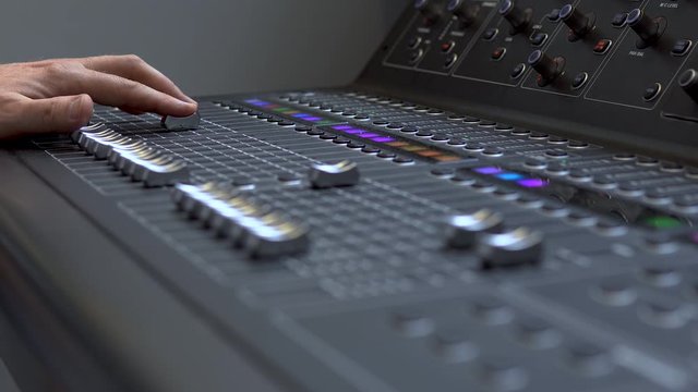Man works on a professional electronic audio mixer. A control panel for tuning sound channels