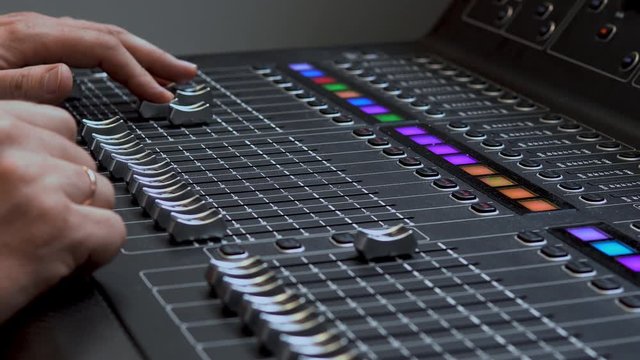 Man works on a professional electronic audio mixer. A control panel for tuning sound channels
