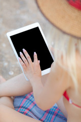 Beautiful and young girl surfing the internet on the beach.