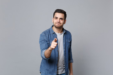 Angry mad sad upset unshaven young man in denim jeans shirt posing isolated on grey wall background studio portrait. People sincere emotions lifestyle concept. Mock up copy space. Screaming gesturing.