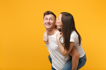 Pretty young couple guy girl in white t-shirts posing isolated on yellow orange wall background....