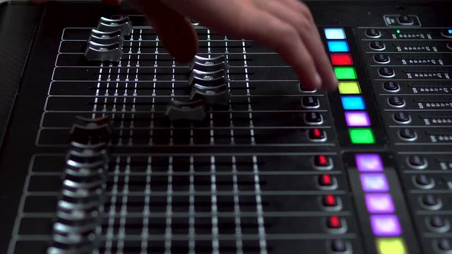 Man works on a professional electronic audio mixer. A control panel for tuning sound channels