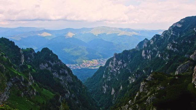 Cinematic shot of the fir, Bucegi mountains, Busteni city and skyline in Romania
