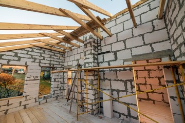 House interior under construction and renovation. Energy saving walls of hollow foam insulation blocks and bricks, ceiling beams and roof frame.