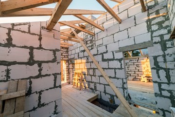 House interior under construction and renovation. Energy saving walls of hollow foam insulation blocks and bricks, ceiling beams and roof frame.