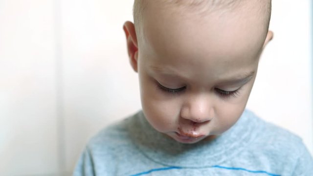 Slow motion baby boy with scratch of lips, nose and chin looks on his parents. Real injury after falling out of perambulator. Video may be used for family or domestic violence